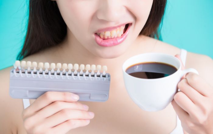 ホワイトニング中にコーヒーを飲む女性