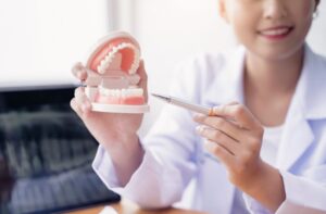 歯のモデル診断を行う笑顔のアジアの歯医者